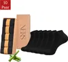 A package of black socks with a cardboard box and bamboo stalks. Produktbild-Vorschau