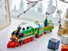 A LEGO Christmas train set is displayed on a white surface with decorative branches and gifts in the background. Produktbild-Vorschau
