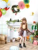 A young girl in a deer costume stands in a festive Christmas-themed room with decorations and gifts. Anteprima dell’immagine prodotto