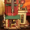 A close-up, detailed view of a miniature wooden model of a gift factory building, with lights on inside. Podgląd zdjęcia produktu