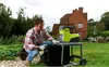 A man is using a green and black electric shredder in a backyard garden setting. Anteprima dell’immagine prodotto