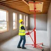 A construction worker is using a red drywall lift to install a piece of wood on the ceiling of a room under construction. Voir les images du produit