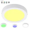 A white round LED ceiling light with a yellow illuminated center, shown with smaller examples of the light illuminated in green and blue, and unlit. Náhľad obrázku produktu
