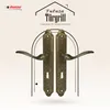A pair of antique gold door handles are displayed against a stylized archway and a patterned background. Produktbild-Vorschau