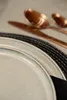 A close-up of a table setting with a plate, placemat, and copper cutlery. Náhľad obrázku produktu