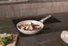 A frying pan with food is on an induction hob in a modern kitchen. Anteprima dell’immagine prodotto