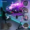 A gaming desk setup with a computer, monitor, chair, and accessories, illuminated by neon lights. Produktbild-Vorschau