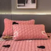 Rosa gesteppte Kissen und Tagesdecke mit schwarz-weißen Herzmustern auf einem Bett, neben einer Zeitschrift und einer Parfümflasche Náhled obrázku produktu