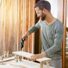 A man is using a Bosch IXO screwdriver to assemble a small wooden shelf outdoors. Podgląd zdjęcia produktu