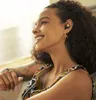 A woman wearing earbuds and jewelry, smiling. Produktbild-Vorschau