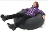 A person sitting in a snow tube on a white background. Produktbild-Vorschau