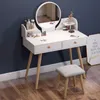 A white vanity table with a round mirror and a stool, set against a dark blue wall and wooden floor. Podgląd zdjęcia produktu