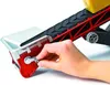 A hand is shown turning a crank on a red and white conveyor belt trailer. Náhled obrázku produktu