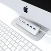 A Satechi USB-C Combo hub desktop is placed on a stand in front of an Apple iMac computer, with a keyboard in the foreground. Náhled obrázku produktu