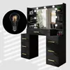 A black vanity table with LED lights and a mirror, featuring drawers and shelves, with a close-up of a light bulb in the corner. Náhled obrázku produktu