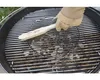 A hand wearing a glove is cleaning a grill with a brush. Anteprima dell’immagine prodotto