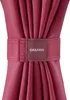 A close-up of a burgundy fabric tie holding together gathered fabric, with a small square label bearing the brand name. Anteprima dell’immagine prodotto