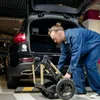A man is loading a stroller into the trunk of a car. Voir les images du produit