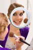 A woman applying makeup in front of a mirror with a ring light. Produktbild-Vorschau