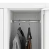 Close-up view inside a white wardrobe or locker, showing a metal hanging rod with two hangers holding clothes. Anteprima dell’immagine prodotto