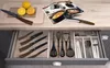 A kitchen counter with a drawer open, showing various kitchen utensils and knives, along with lemons and a magazine. Anteprima dell’immagine prodotto