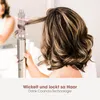 A woman is using a hair styling tool to curl her hair. Voir les images du produit