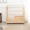 A wooden toddler bed with a mattress is shown in a room with white paneled walls and a patterned rug. Anteprima dell’immagine prodotto