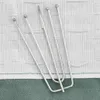 A close-up view of several metal curtain hooks resting on a textured fabric background. Podgląd zdjęcia produktu