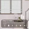 A close-up view of a window with blinds, a bedside table with a lamp and decorative items, and a bed frame. The image highlights the ease of installation and features of a smart curtain motor. Podgląd zdjęcia produktu