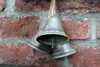 Three small silver bells hang from a rope against a brick wall. Anteprima dell’immagine prodotto