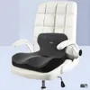 A dark gray orthopedic seat cushion with a lumbar support is placed on a white office chair. Produktbild-Vorschau
