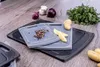 A close-up shot of two cutting boards with various ingredients like onions, garlic, potatoes, peppercorns, and parsley arranged on a wooden table. Produktbild-Vorschau