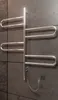 A chrome electric towel warmer mounted on a dark tiled wall with a visible power cord and outlet. Podgląd zdjęcia produktu