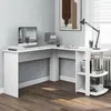 A white L-shaped desk with shelves is set up in a room with a light gray wall and a wooden floor. A computer monitor, books, and a desk lamp are on the desk. Anteprima dell’immagine prodotto