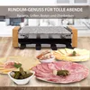 A raclette grill with various food items like cheese, meat, and pickles arranged in front of it. Produktbild-Vorschau