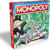 A Monopoly board game box is shown at an angle, with the front and side panels visible. The background is a blurred cityscape with money falling. Produktbild-Vorschau