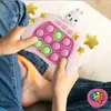 A child is holding a pink and white electronic game with a rabbit on top, surrounded by yellow stars. Produktbild-Vorschau