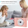 A young girl receives a gift from a woman, with a pink digital camera in the foreground. Náhled obrázku produktu