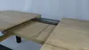 A close-up view of an extendable table with a wooden surface and metal sliding mechanism. Náhled obrázku produktu