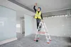 A construction worker is using a laser level on a ladder to mark lines on the ceiling of a room under renovation. Náhľad obrázku produktu