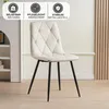 A cream-colored upholstered dining chair with diamond tufting and black metal legs, displayed in a minimalist interior setting. Produktbild-Vorschau