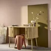 A wooden desk with a stool in a room with pink and olive green walls. Produktbild-Vorschau