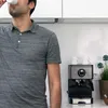 A man drinks coffee in a kitchen next to an espresso machine. Produktbild-Vorschau