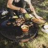 A person is grilling burgers on a large round grill outdoors. Anteprima dell’immagine prodotto