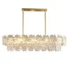 A rectangular chandelier with multiple tiers of clear, leaf-shaped glass elements hanging from a gold-colored metal frame. Anteprima dell’immagine prodotto