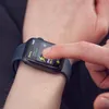 A person's hand is touching a smartwatch on their wrist. Produktbild-Vorschau