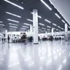 People walking through a modern, well-lit interior space, possibly a train station or airport terminal, with a polished floor reflecting the lights. Náhľad obrázku produktu