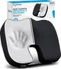 A black and white orthopedic and ergonomic seat cushion is shown in a studio setting with its packaging in the background. Produktbild-Vorschau