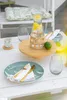 A table setting with plates, cutlery, glasses, and a carafe of water with lemon slices, suggesting an outdoor dining or entertaining scene. Anteprima dell’immagine prodotto