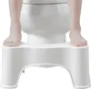 A child's feet are shown standing on a white toilet stool in front of a toilet. Podgląd zdjęcia produktu